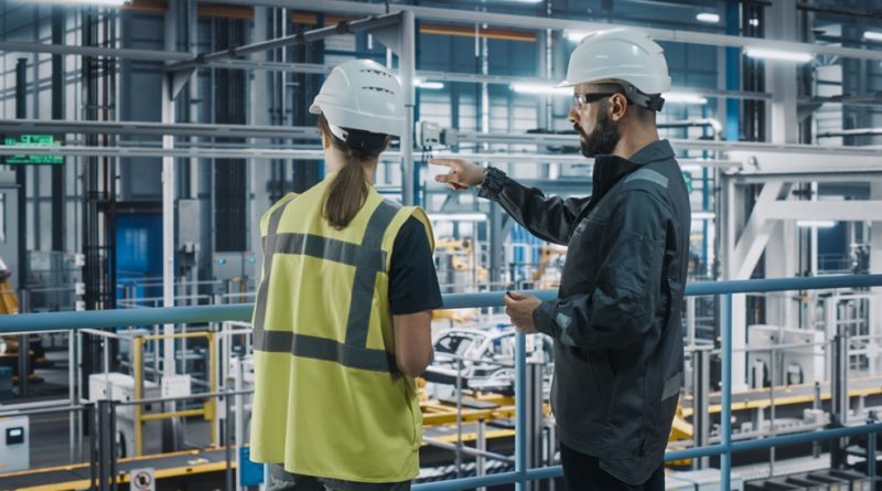 Two workers study automotive production line