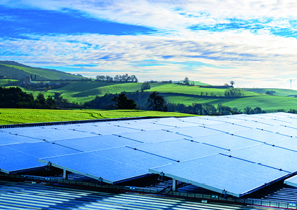 a utility-scale solar farm array installed across a vast countryside landscape