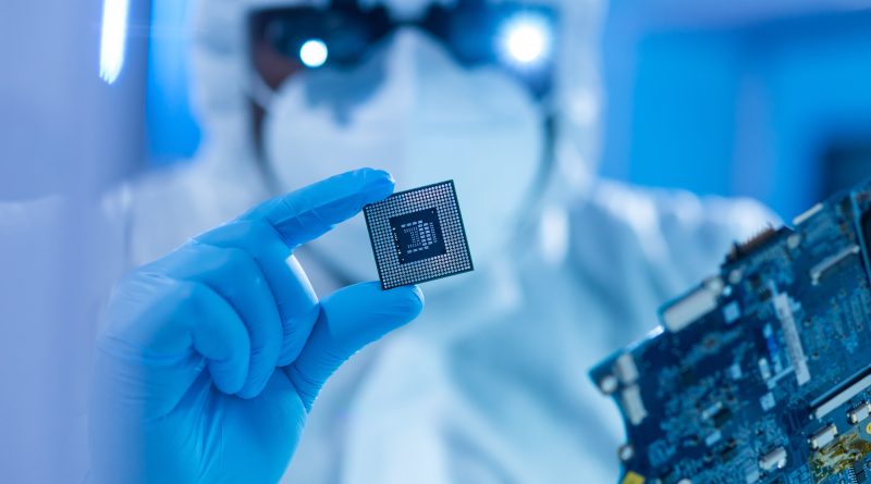 Engineers working inside a modern semiconductor fabrication plant with automated wafer processing equipment.