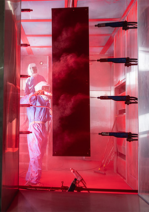 an industrial electrostatic powder coating booth where automated spray guns apply a charged dry finish onto a metal workpiece