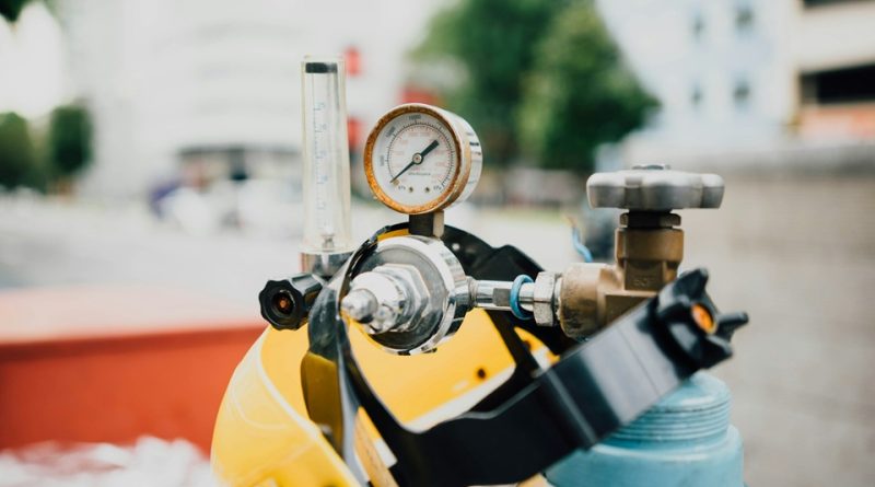 Industrial gas cylinder fitted with a pressure regulator and flow gauge for manufacturing applications.