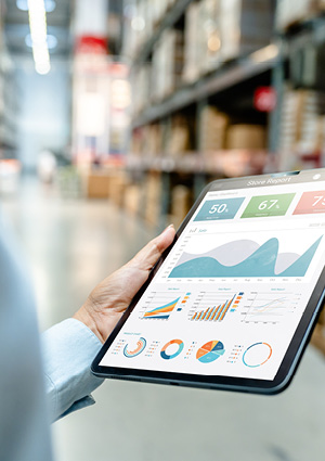 a person holding a digital tablet displaying inventory analytics and data charts