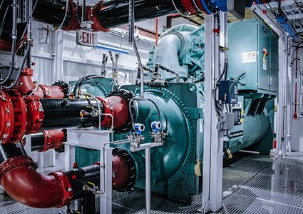 an industrial water chiller system with large green centrifugal machinery and red-valved connecting pipes