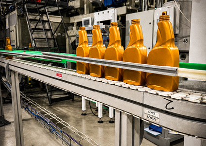 orange plastic bottles moving along an automated conveyor belt