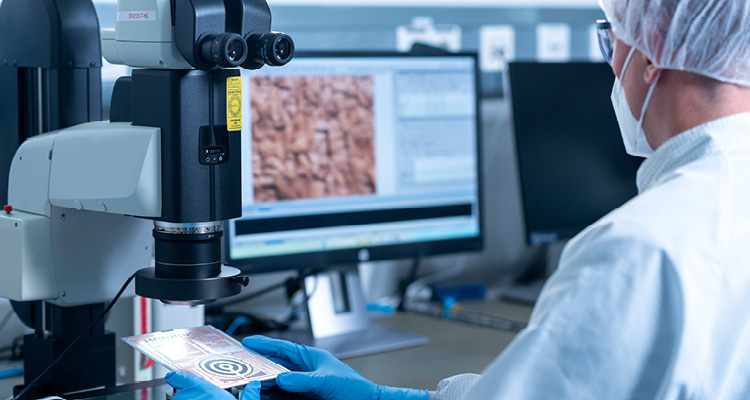 shows a scientist or technician in a sterile laboratory setting operating a large digital microscope system
