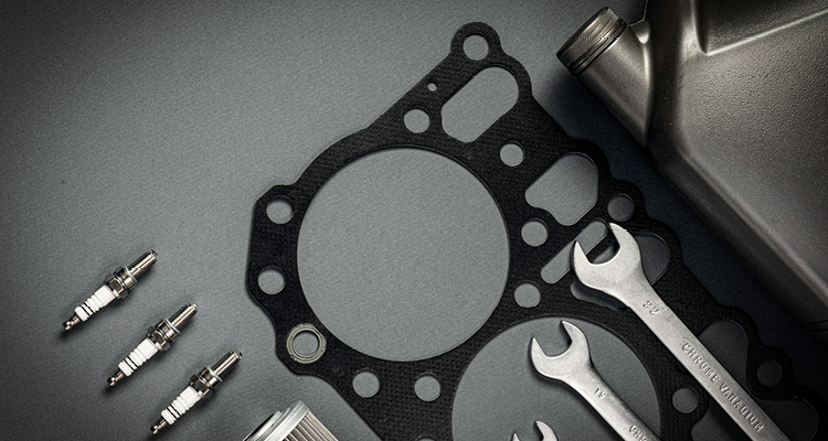 a collection of car maintenance parts and tools, including a head gasket, spark plugs, and wrenches