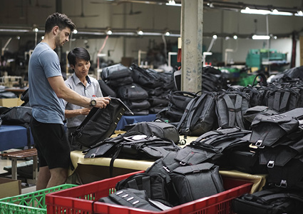 two individuals examining black backpacks