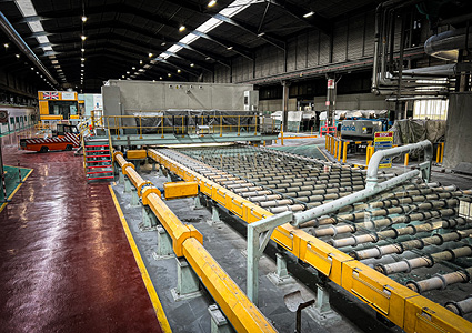 an industrial manufacturing facility with a heavy-duty roller conveyor and cooling bed system