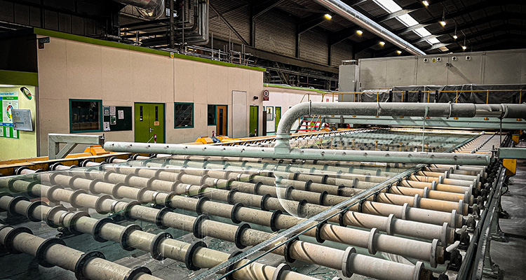 a continuous ribbon of flat glass moving along a roller conveyor table