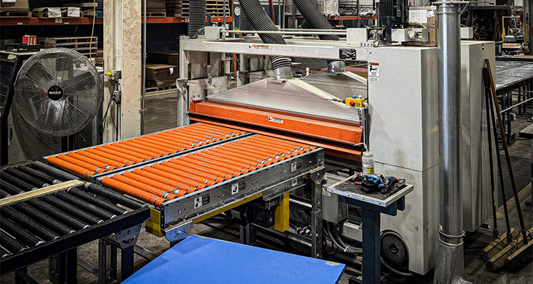an industrial laminating or adhesive coating machine with orange roller conveyors