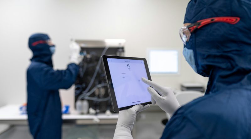 Medical device manufacturing professionals using digital equipment in a cleanroom production environment.