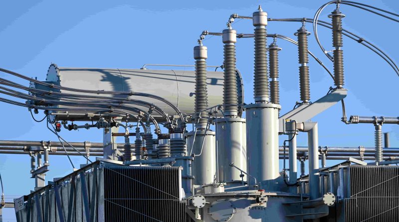Electrical substation with high-voltage transformer bushings and insulators against a clear sky