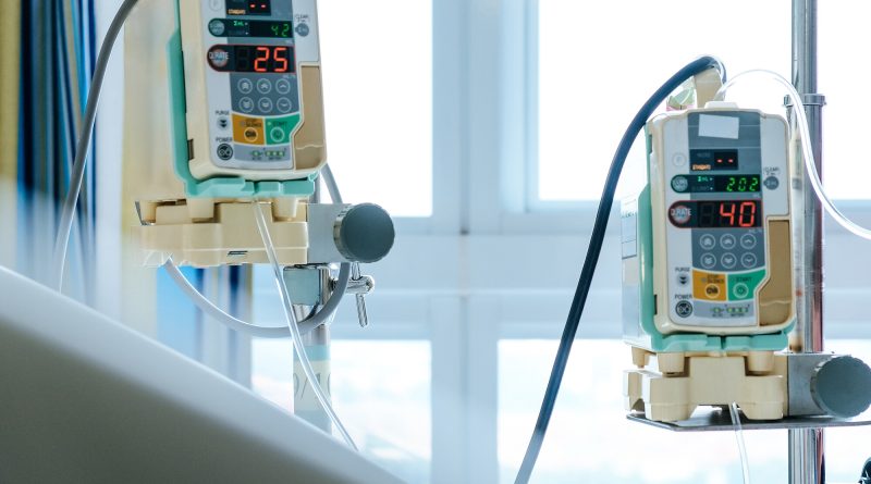Two infusion pumps mounted on an IV pole in a hospital room, devices that can use sensors to detect air bubbles in fluid lines