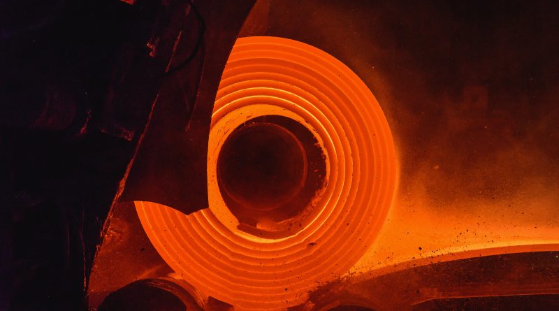 Glowing hot steel strip running along rollers inside a steel rolling mill